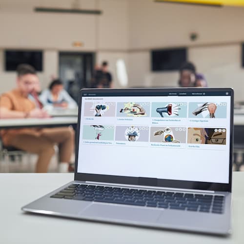 Startchancen-Programm Ein Laptop steht in einem Klassenzimmer auf dem das digitale Produkt "Module zu Medienbildung & Präsentieren" auf dem Bildschirm zu sehen ist.
